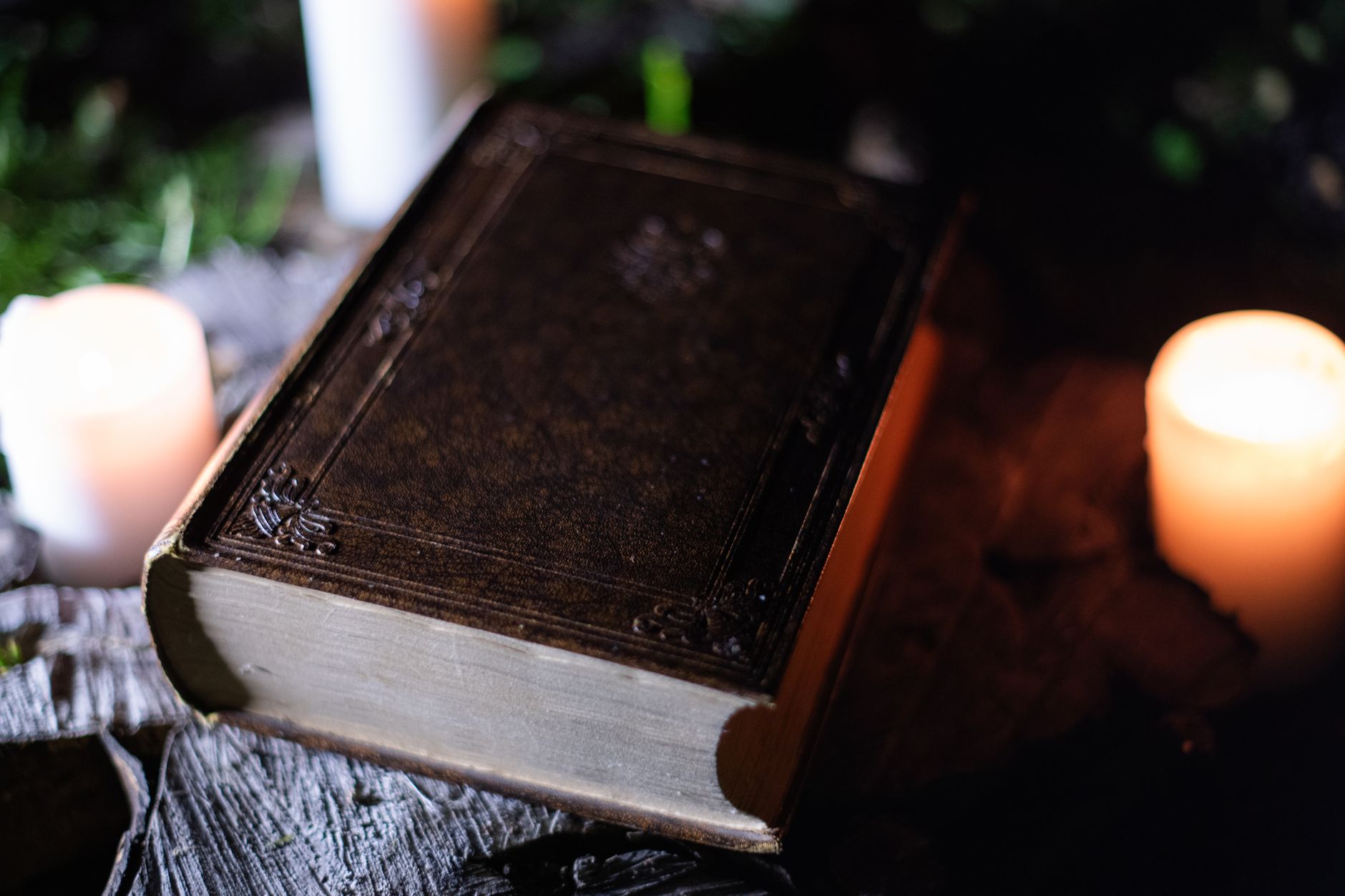 Ancient leather book by candlelight, central to a dark academia horror setting